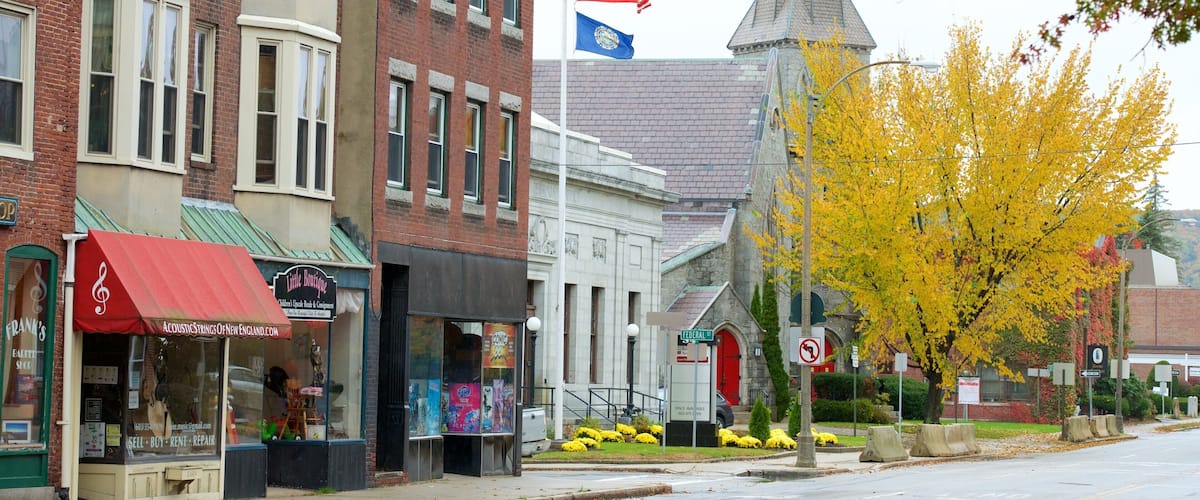 A street with historic buildings, a church steeple, and autumn foliage.