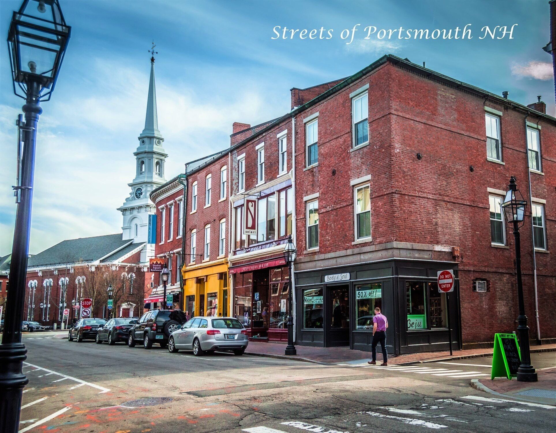 A street in Portsmouth, NH, with brick buildings, a church steeple, and a 'Do Not Enter' sign.
