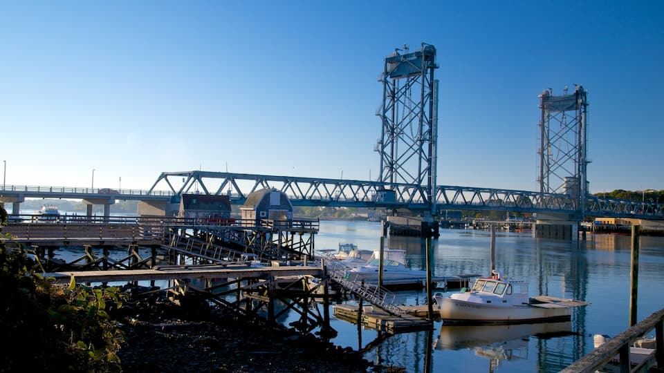 A bridge over a calm river with boats docked at the pier.
