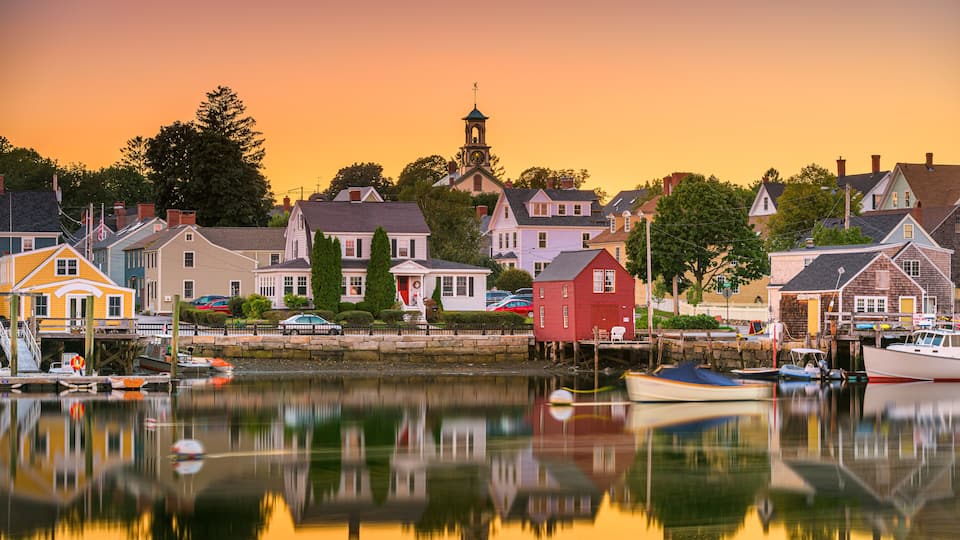A harbor with boats, a church with a clock tower, and colorful houses.