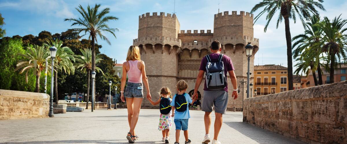 A family walking on a paved pathway with a historic castle in the background.