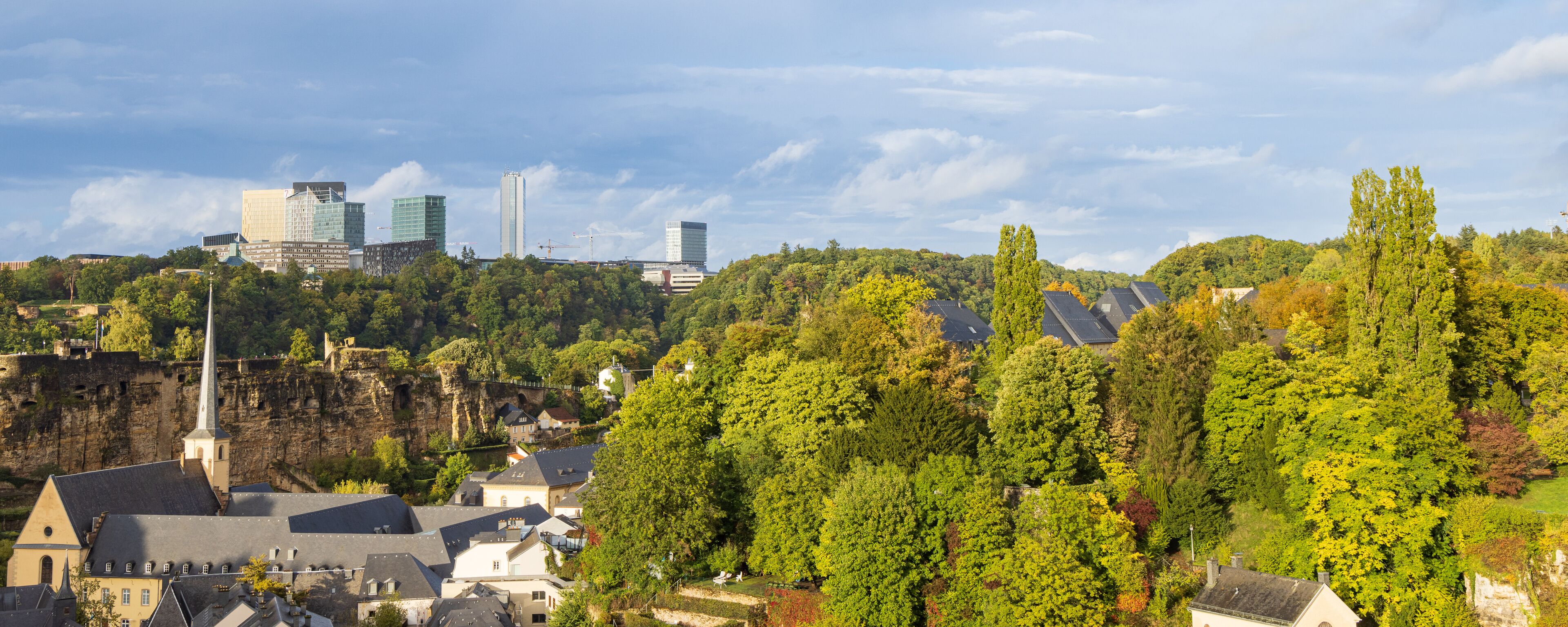 A cityscape with modern buildings and a historic church on a hillside.