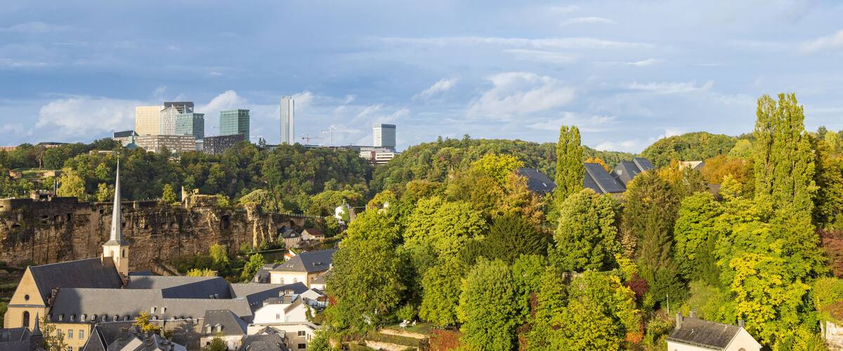 A cityscape with modern buildings and a historic church on a hillside.