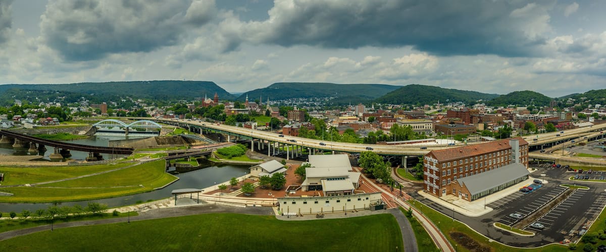 A river flowing through a town with a bridge and a large building with a sign.