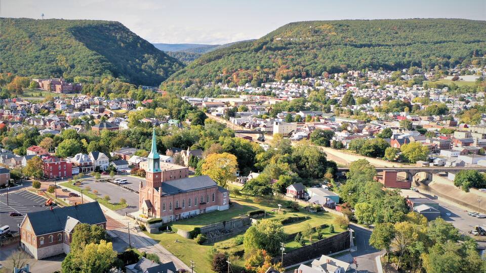 A town with a prominent church, a bridge, and rolling hills in the background.