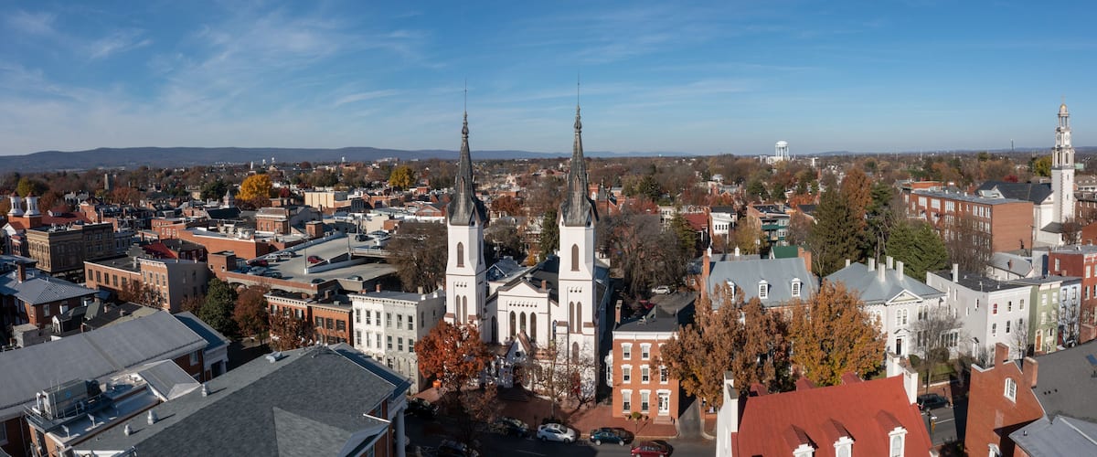 A cityscape with prominent church spires, historic buildings, and a distant water tower.