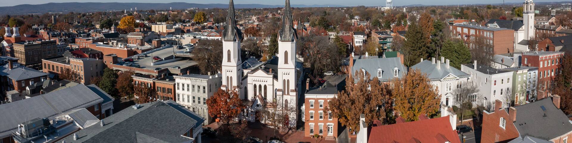 A cityscape with prominent church spires, historic buildings, and a distant water tower.