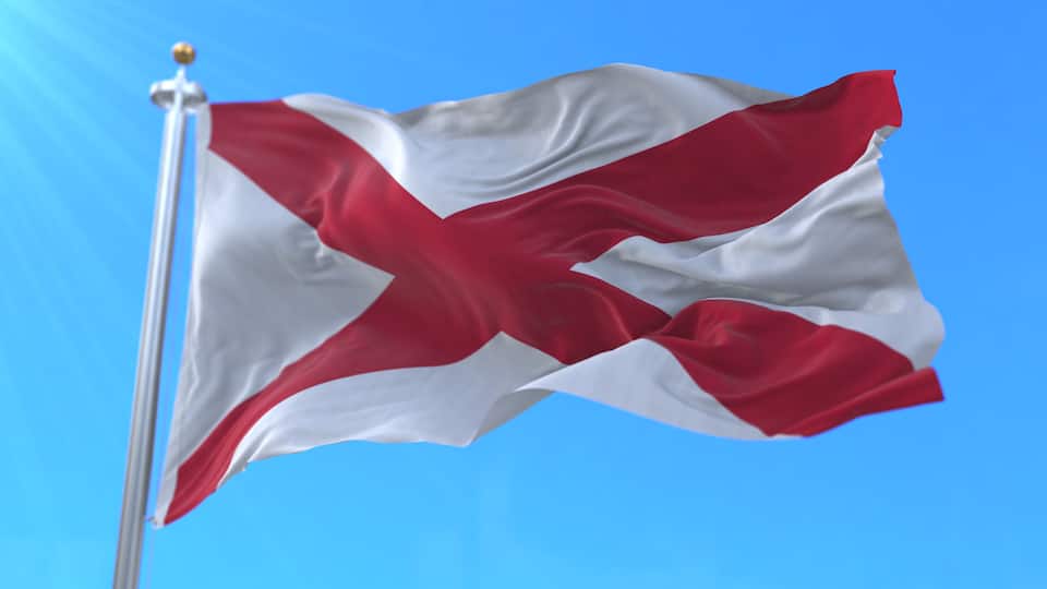 A flag on a flagpole against a clear blue sky.