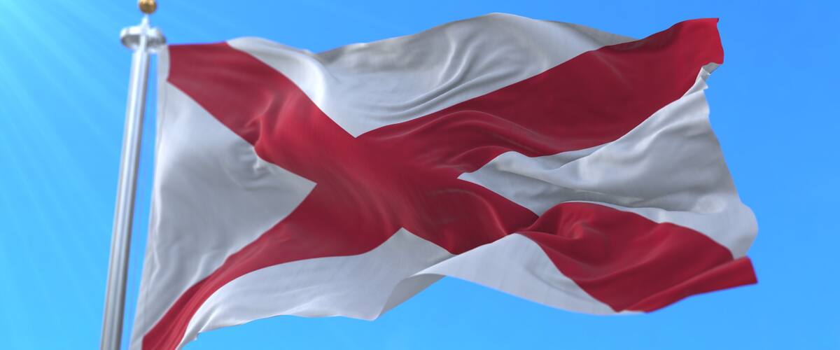 A flag on a flagpole against a clear blue sky.