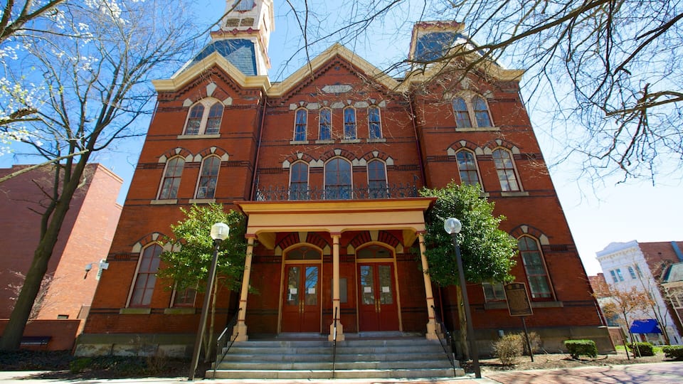 A large red brick building with a tower, arched windows, and a covered entrance.