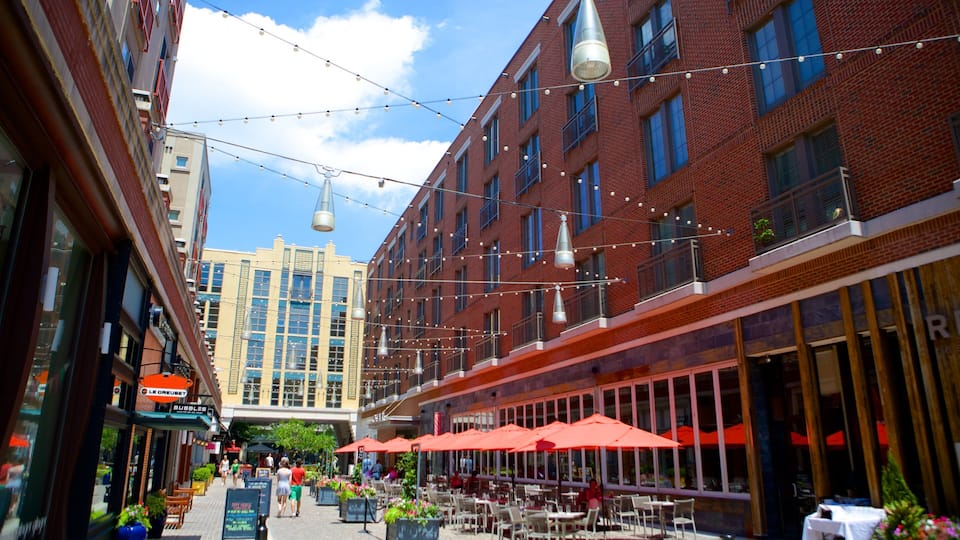 A street with outdoor seating, brick buildings, and string lights.