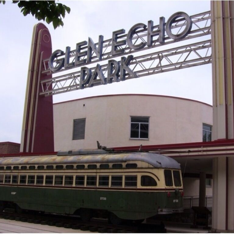 A vintage train at Glen Echo Park with a large sign above.