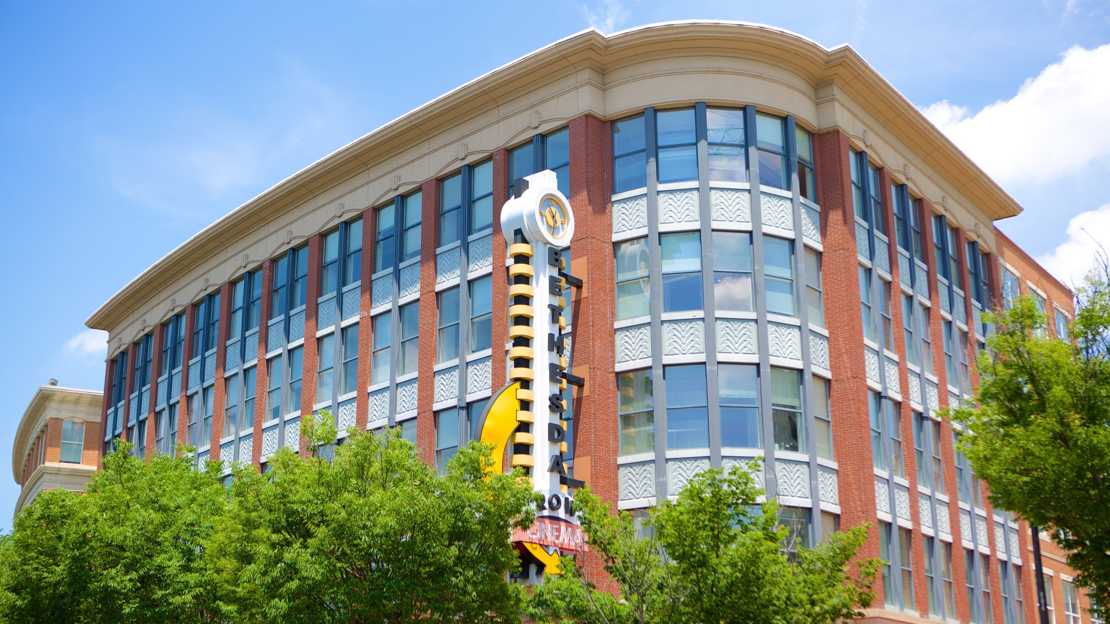 A large, multi-story building with a curved facade, large windows, and a prominent clock tower.
