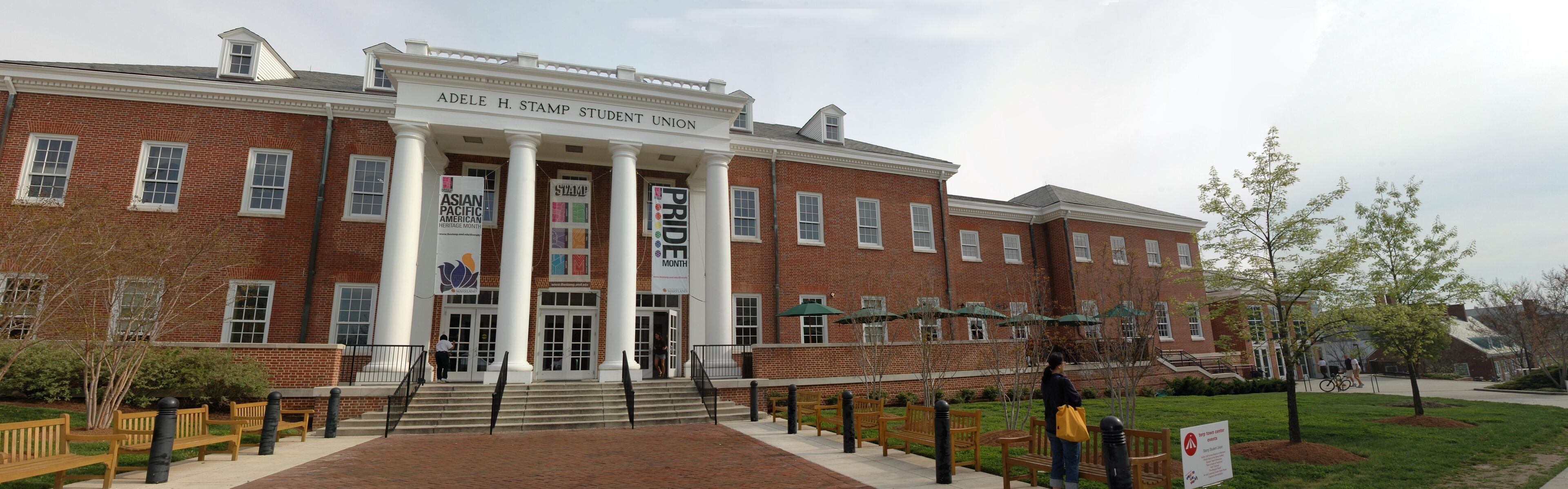 A brick building with columns and banners for Asian Pacific American Heritage Month and Pride Month.
