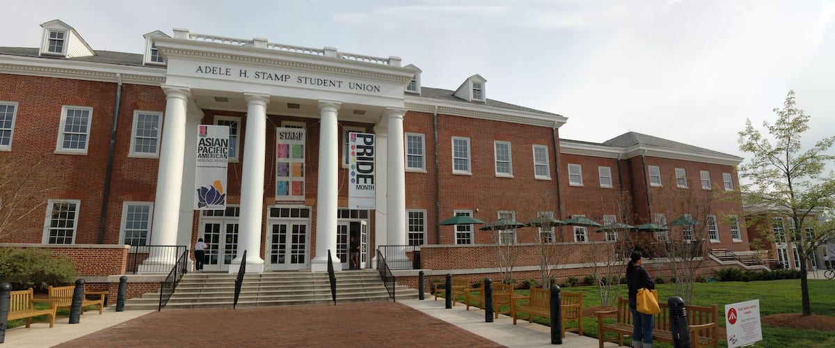 A brick building with columns and banners for Asian Pacific American Heritage Month and Pride Month.