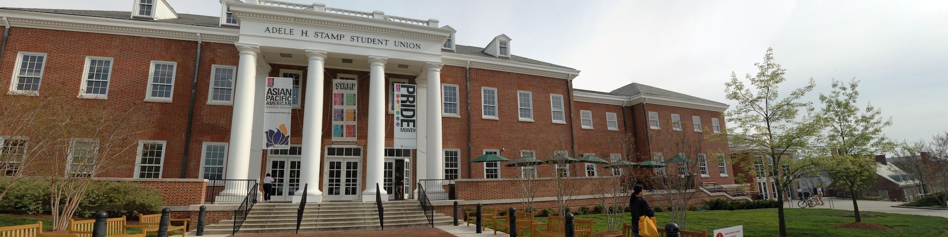 A brick building with columns and banners for Asian Pacific American Heritage Month and Pride Month.