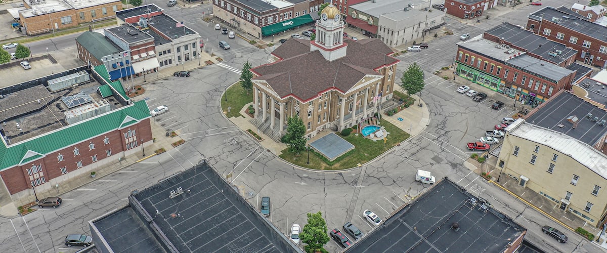 An aerial view of a town with a prominent church with a clock tower, surrounded by various buildings and streets.