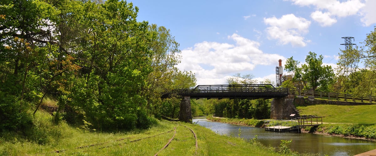 A railway track, a river, a bridge, and a power pylon.