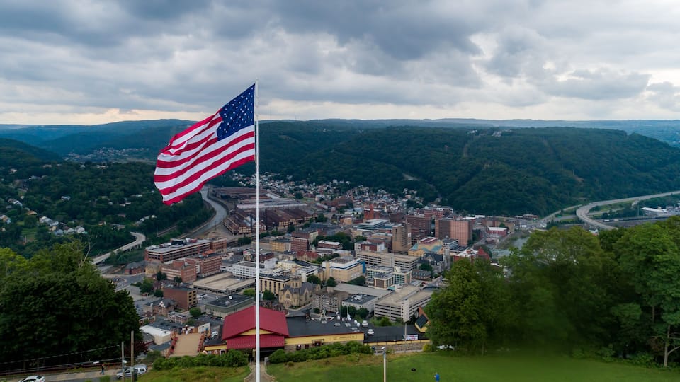 An American flag on a flagpole with a cityscape in the background.