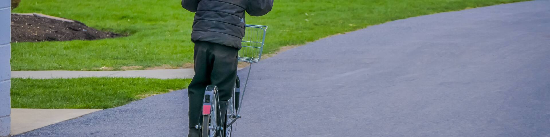 Unidentified little amish boy playing with his roller bikes or scootersin the backyard of his house