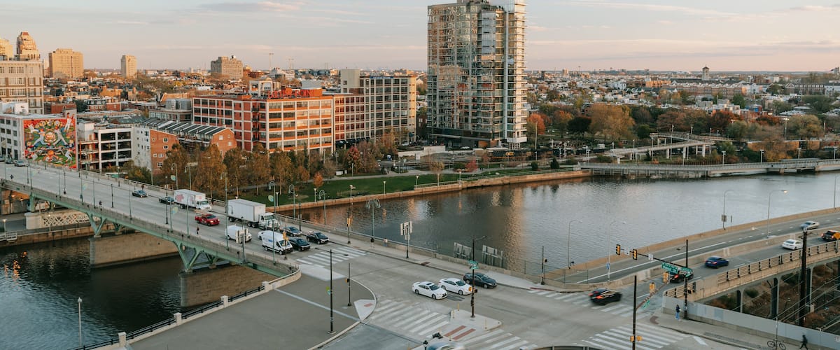 A cityscape with a river, a bridge, and various buildings including a tall, modern structure.