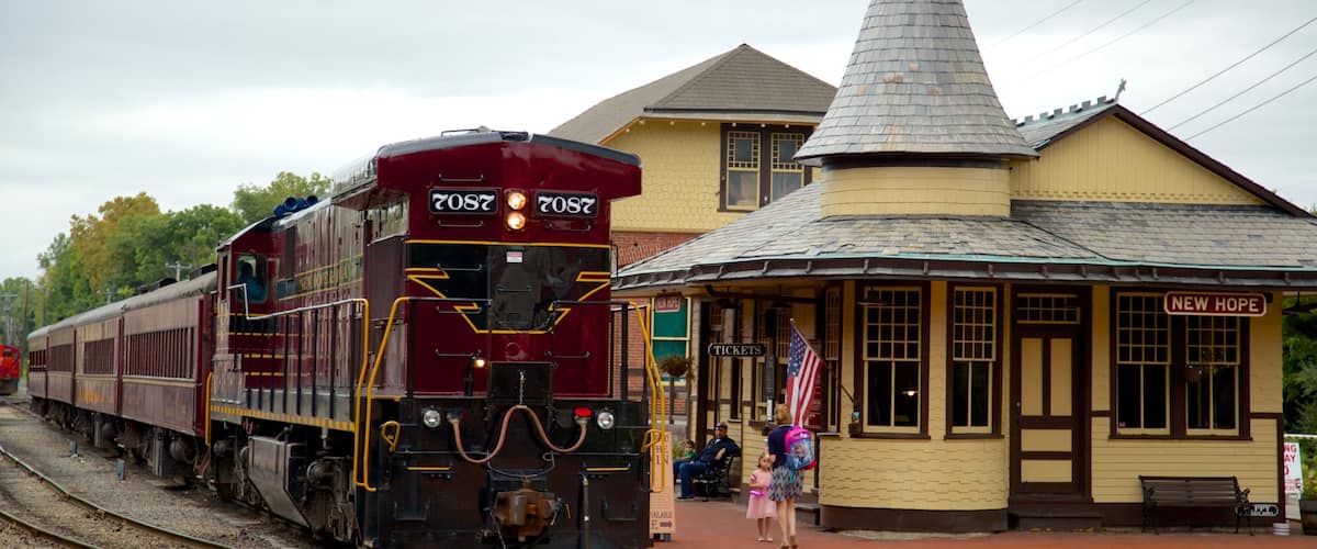 A steam locomotive at a train station with a church steeple and a sign reading "New Hope".