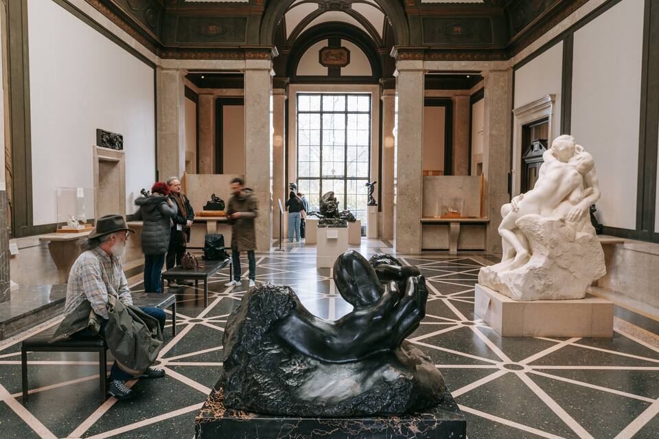 A museum interior with marble floors, classical architecture, and sculptures.