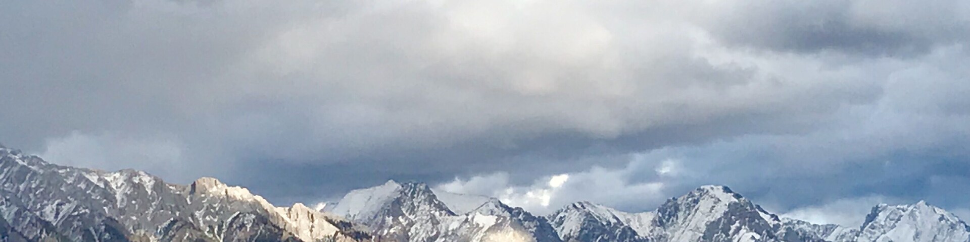 A mountain range with snow-capped peaks and a forested foreground.