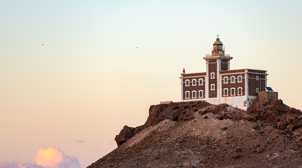 Un phare perché sur une colline rocheuse, sous un ciel dégagé.