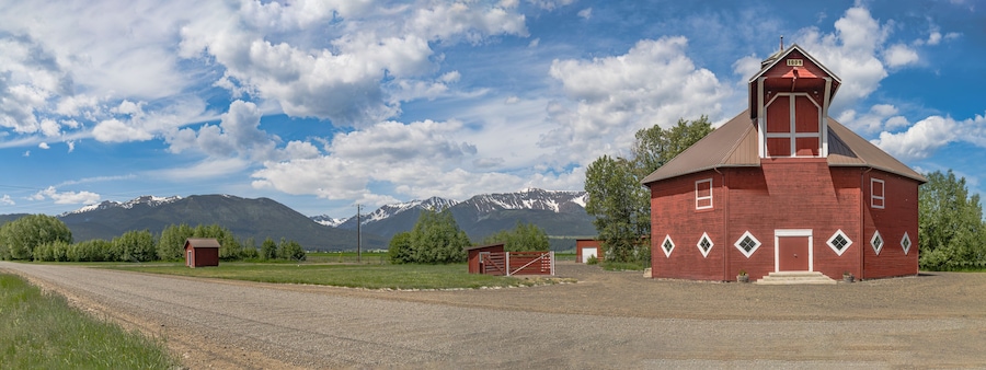 Iconic wooden red barn in Eastern Oregon with the Cascade Mountains in the background