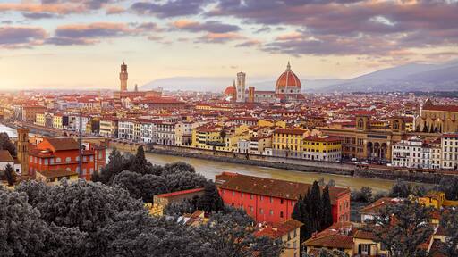 Florence (Firenze, Italy. Sunset panorama. Evening view at ancient city. Famous Ponte Vecchio bridge on river Arno scenic clouds and sky. Duomo Santa Maria del Fiore cathedral, Palazzo Tower