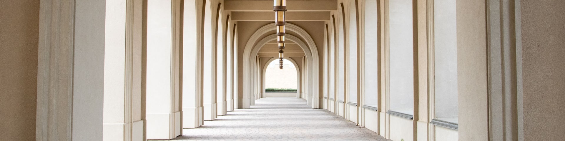 A long corridor with arches and a hanging light fixture.