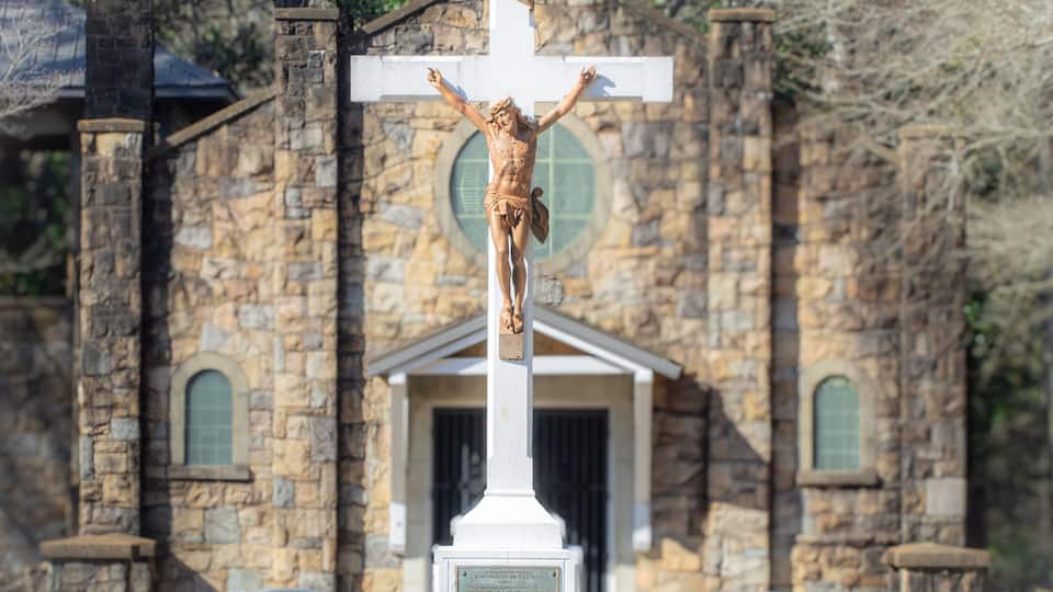 A stone church with a crucifixion statue in front.
