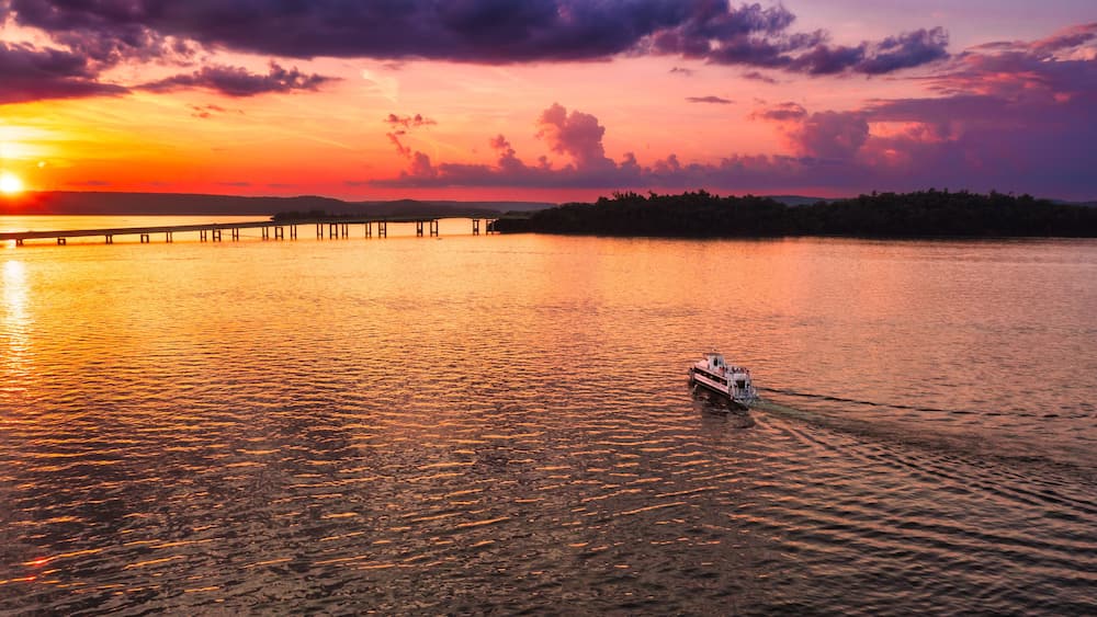 A sunset over a calm lake with a pier extending into the water.