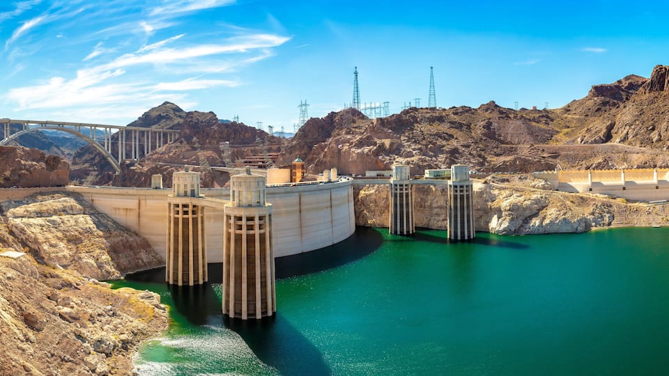 A hydroelectric dam with a bridge, rocky terrain, and a reservoir.