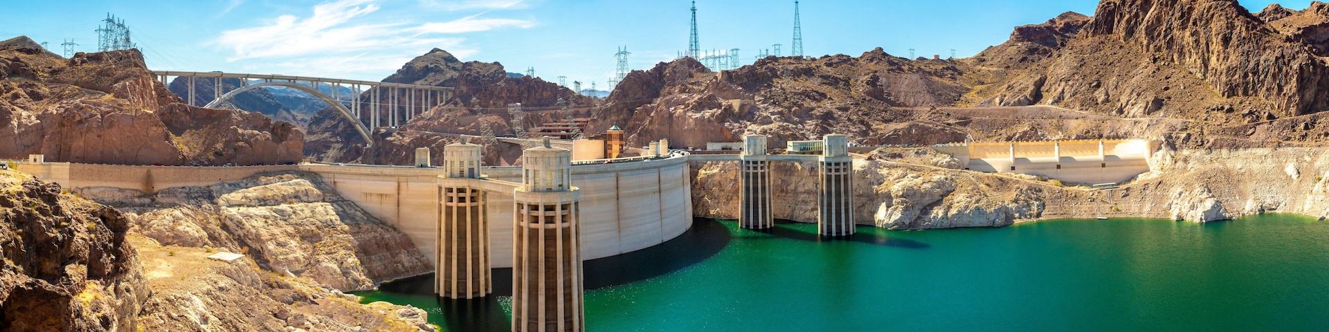 A hydroelectric dam with a bridge, rocky terrain, and a reservoir.