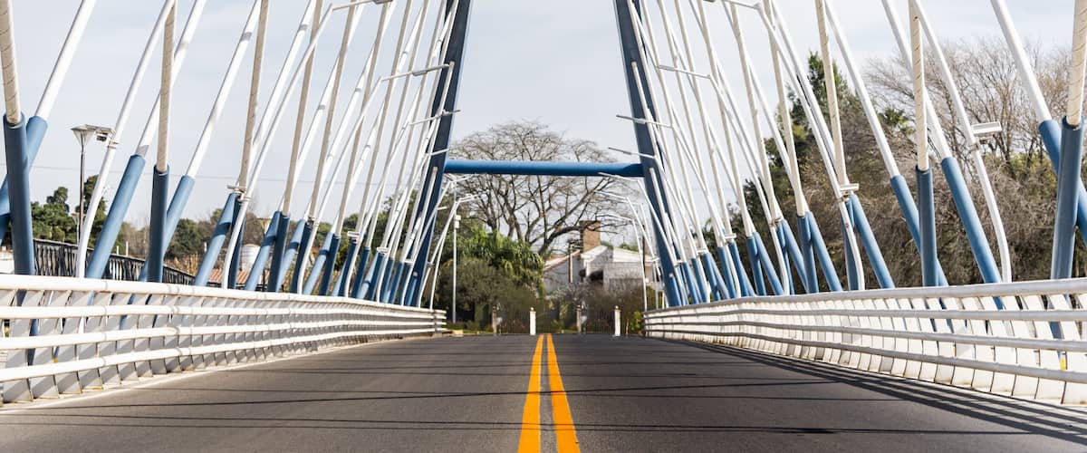 A bridge with white and blue railings and a yellow centerline.