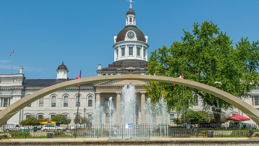 A historic building with a clock tower, a fountain, and a large archway.