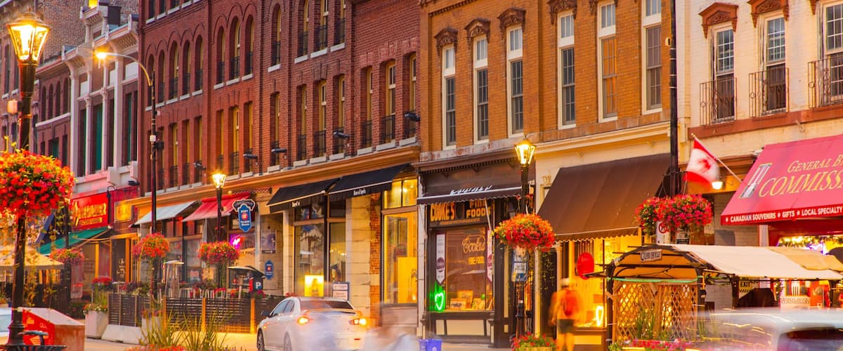 A street with brick buildings, storefronts, and flower planters.