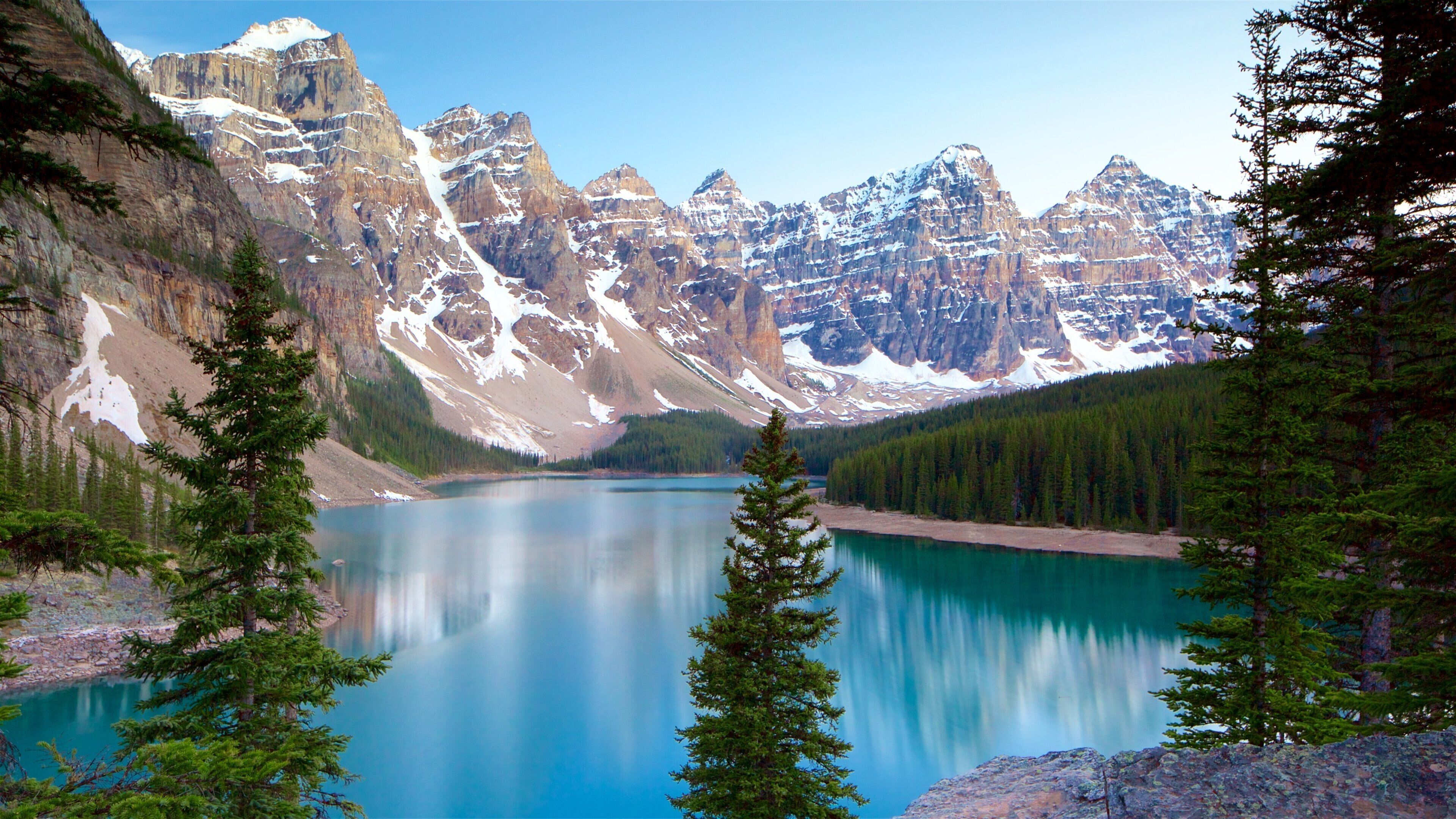 A mountain lake surrounded by snow-capped peaks and dense forest.