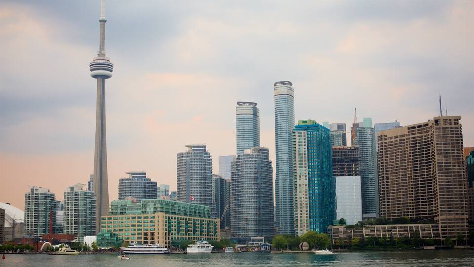A city skyline with modern skyscrapers, a prominent tower, and a waterfront with boats.