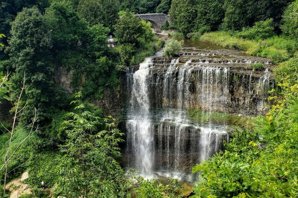 A waterfall cascading over a rocky cliff surrounded by lush greenery.