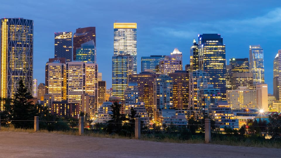 A city skyline at dusk with illuminated buildings and a clear sky.