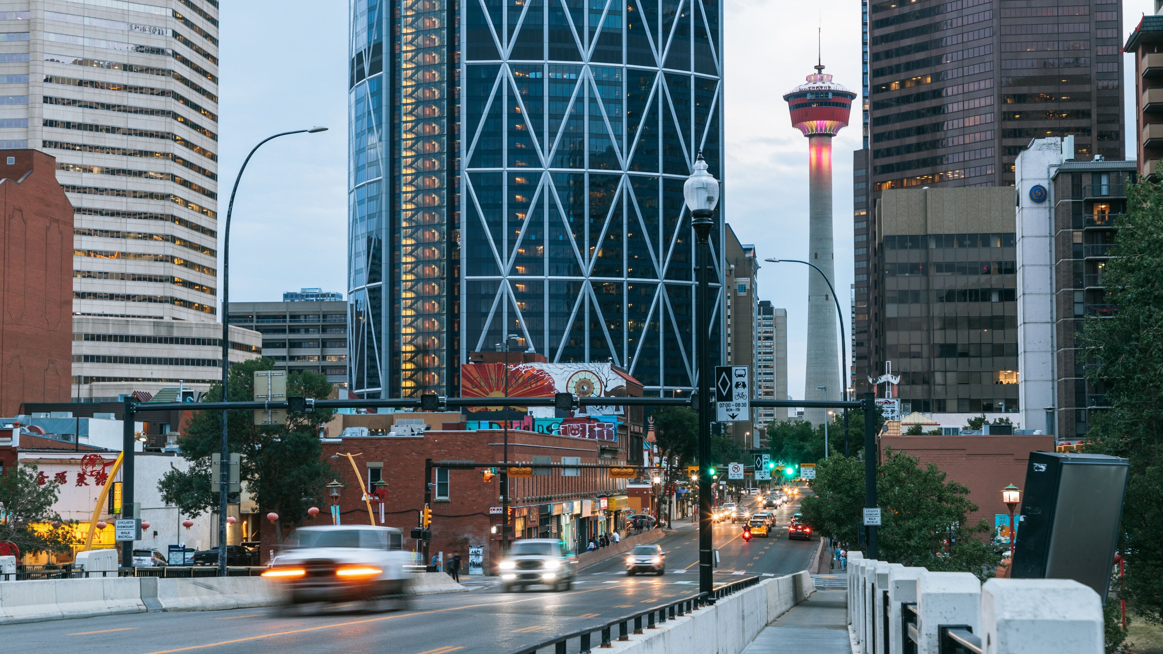 A cityscape with tall buildings, a prominent tower with a lit top, and a busy street with cars.