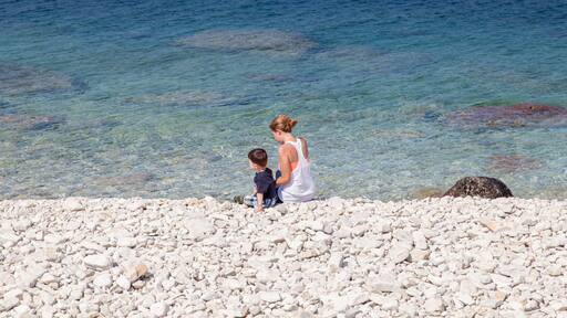 A pebbly beach with clear water and a rocky outcrop.