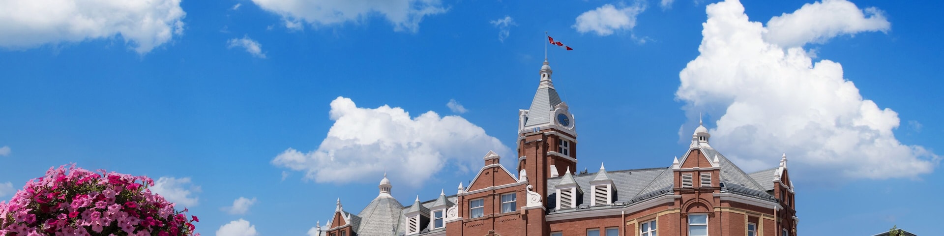 A historic building with a clock tower, surrounded by a clear blue sky and fluffy clouds.