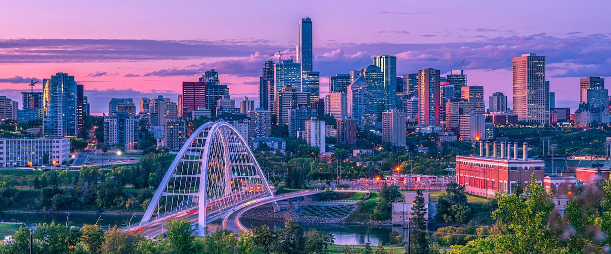 Skyline of Edmonton at dusk with a pink glow and the Walterdale Bridge crossing the North Saskatchewan River in the River Valley; Edmonton, Alberta, Canada