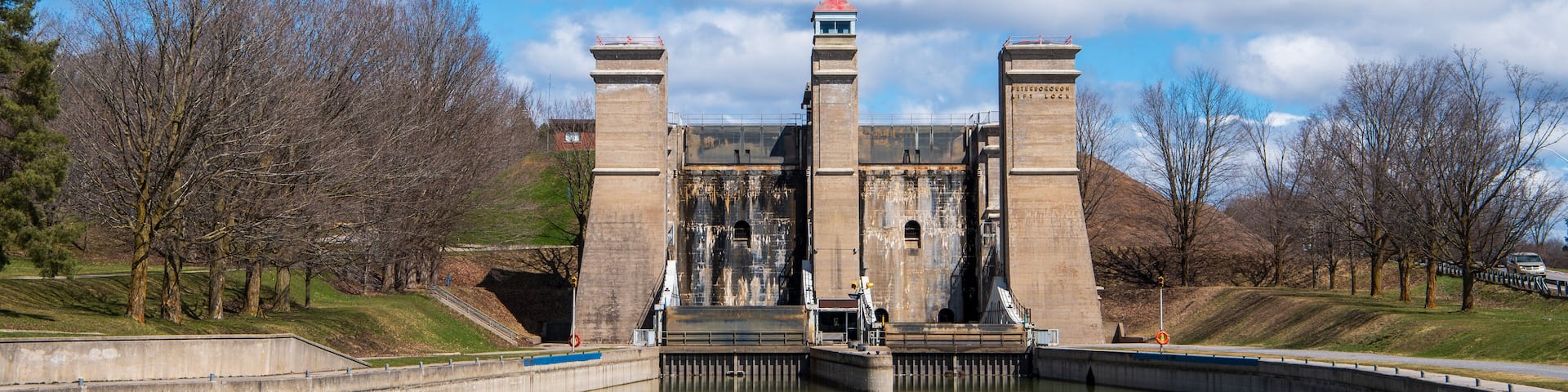 A large dam with two towers, surrounded by trees and a clear sky.
