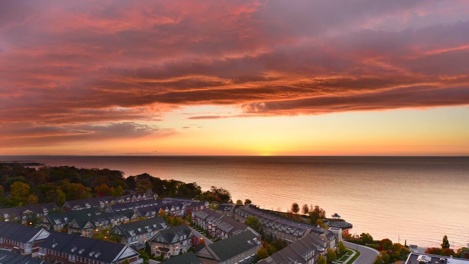 A coastal residential area with houses and a body of water during sunset.