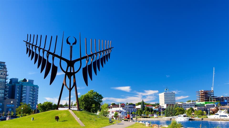 A large metal sculpture in a park with a cityscape in the background.